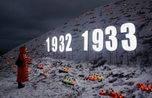 A woman stands in front of candles placed on snowy ground
