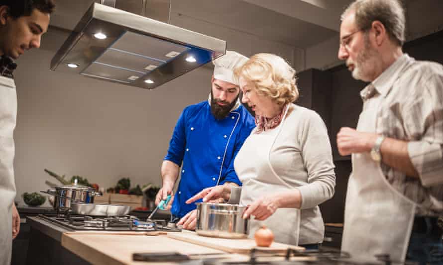 Chef assisting a cooking classSenior couple preparing for cooking challenge. Chef showing them some tips and tricks