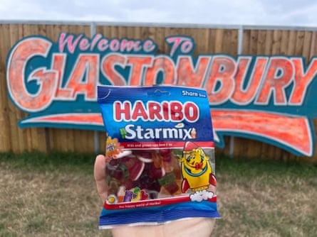 A packet of Starmix in front of a fence painted with “welcome to glastonbury”