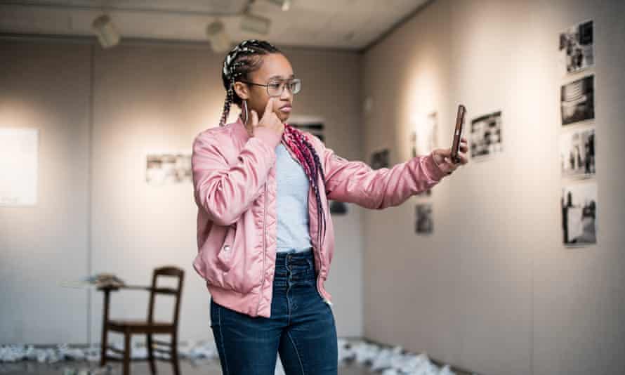Lai Lai Bonner, 19, poses for a selfie in front of a Shooting Without Bullets exhibit.