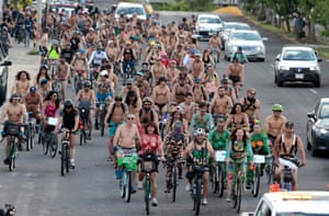 Dozens of cyclists, many wearing only shorts or bikinis