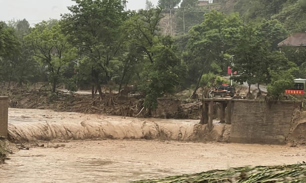 Ένα αυτοκίνητο στέκεται δίπλα σε ένα τμήμα μιας γέφυρας που παρασύρθηκε από πλημμύρες στο Qingyang, βορειοδυτική Κίνα