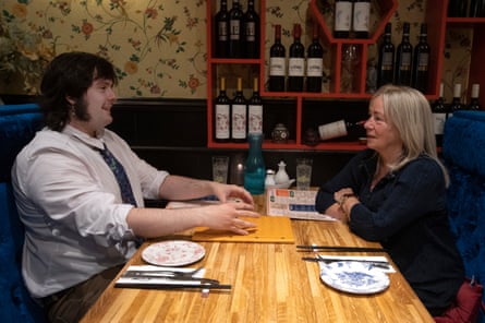 Lucas and Marie-Rose sitting opposite one another chatting at a restaurant table