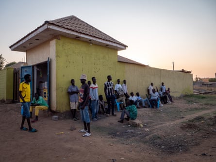 22 young men sit and stand around on a street corner