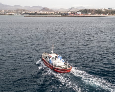 Crew members wearing hazmat suites are seen on board of a boat heading towards the port from the cruise ship MV Hondius.