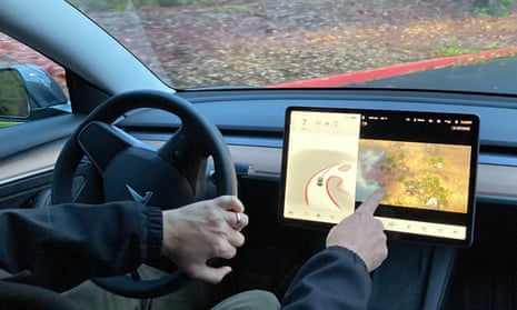 A man drives a Tesla vehicle while playing a video game on the car's center console display.