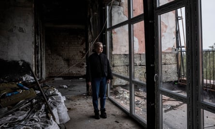 Yana Psariova looks out of new windows as she stands in her destroyed apartment in Irpin