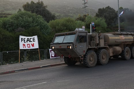 A military vehicle passing a Peace Now banner during a protest against the war and the Israeli government, in the Kiryat Shmona in northern Israel