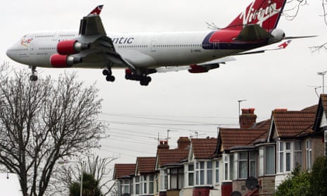 A Virgin Atlantic plane flies over houses in the village of Stanwell outside Heathrow airport
