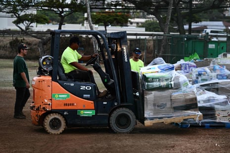 A worker drives a forklift while preparing donated goods for distribution outside of a shelter at War Memorial Stadium in Wailuku.