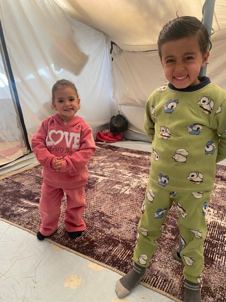 Rose and Karim smile as they stand on a rug inside the tent