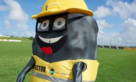 A mascot dressed as a lump of coal, wearing a yellow vest and hard hat and standing in a grassy field