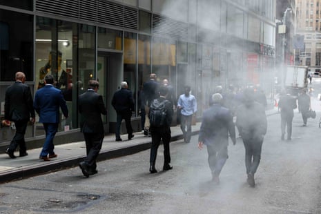 Pedestrians near the New York Stock Exchange walk past buildings amid thick smoke or steam