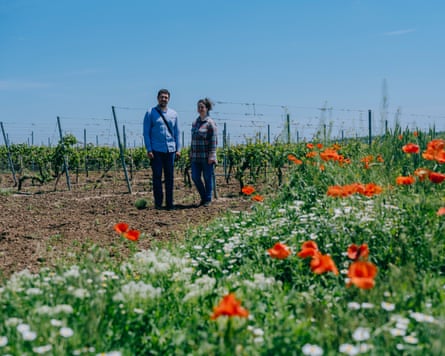 Olha Romashko and Oleksandr Pashkovsky stand on a field surrounded by flowers
