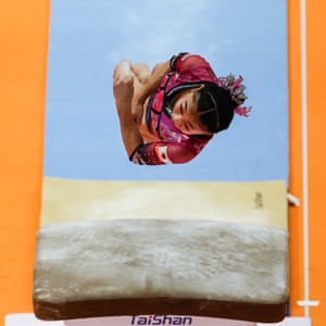 View looking directly down at Rina Kishi as she leaps in the air above a gymnastic bounce board
