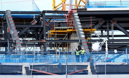 A couple of construction workers watch on before kick-off in an uncompleted section of the ground.