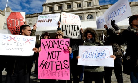 people hold signs with slogans like ‘homes not hotels’