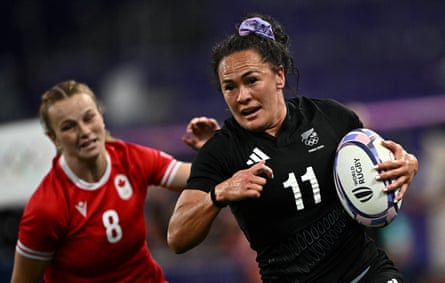 Portia Woodman-Wickliffe of New Zealand runs with a rugby ball, pursued by Carissa Norsten of Canada.