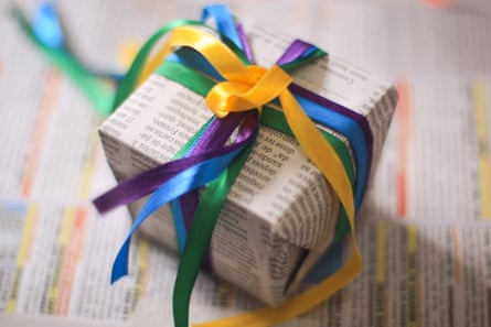 A small gift wrapped in newspaper adorned with multicoloured ribbons