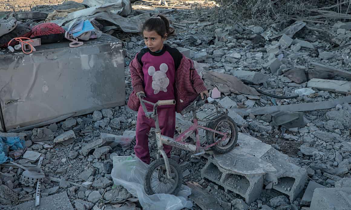 A Palestinian girl is seen among the rubble holding a bike after Israeli bombardment in the Maghazi refugee camp in Gaza