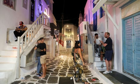 Tourists in front of shops and bars in Mykonos, closed under curfew rules.