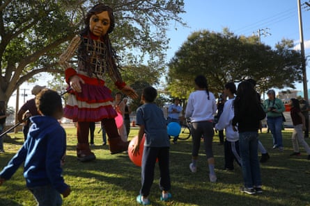 Little Amal plays with migrant children in a park during her journey along the US-Mexico border in El Paso, Texas, on 25 October.