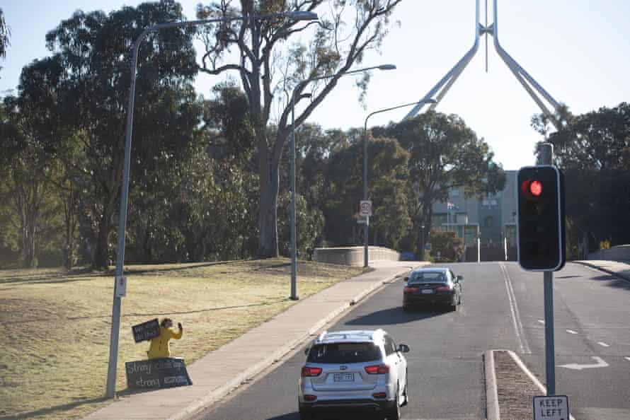 Climate protestor Frances waves to passing traffic at the entrance to Parliament House.