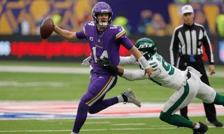 Sam Darnold, the Vikings quarterback in purple, prepares to throw despite the tackle from New York Jets’ Will McDonald in white.