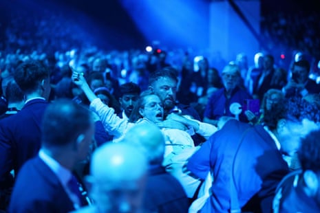 A woman is carried by a man among a crowd of people.