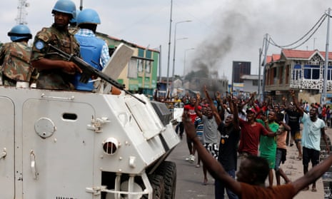 Residents chant slogans against the president as UN peacekeepers patrol during unrest in the streets of the capital, Kinshasa