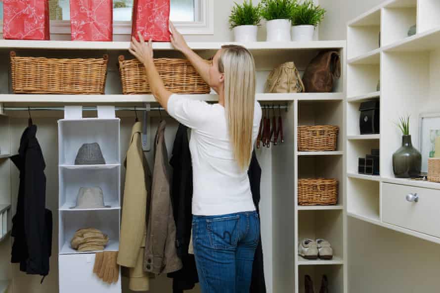 A woman arranging a wardrobe zone with coats, shoes, scarves and hats. 