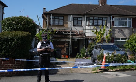 A police officer and emergency tape outside a semi-detached house