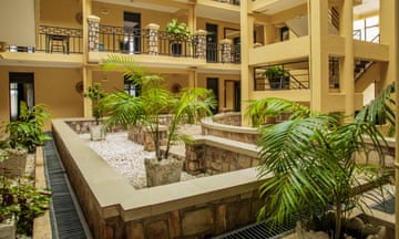 An inside courtyard with rooms opening off different levels and potted palms on the floor