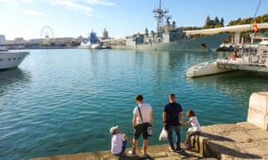Family at Muelle Uno, quay in the port of Malaga, with two warships in background, Andalusia, Spain.