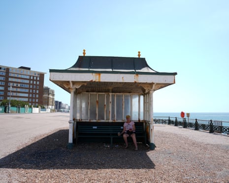 A person shelters from the heat of he sun by sitting in the shade of a beach shelter in Hove, on the south coast of England.