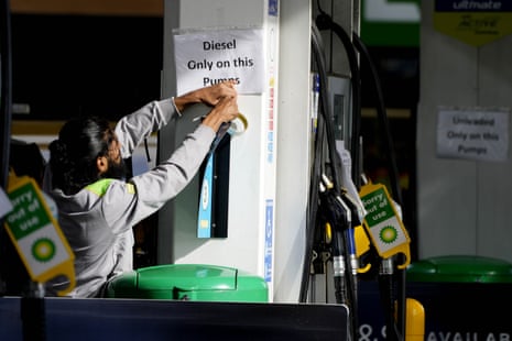 A petrol station employee puts up signs at a petrol station in London today