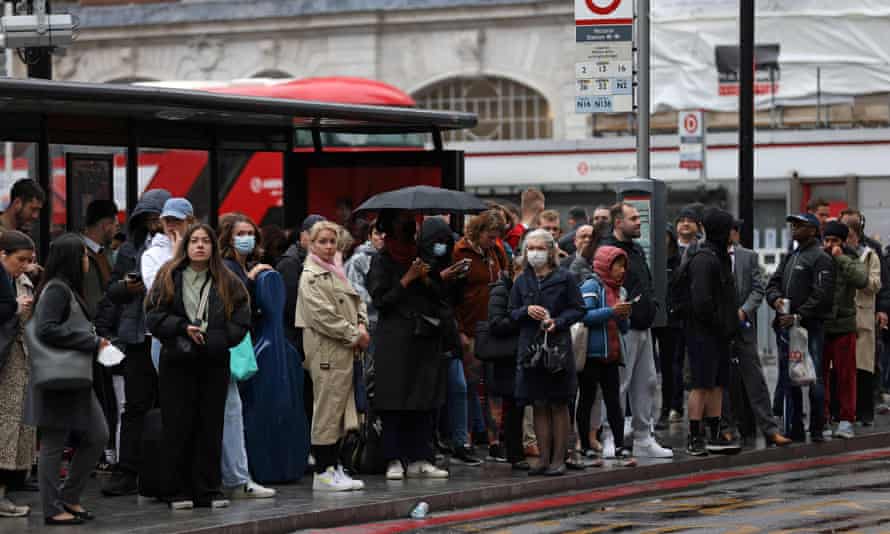 Commuters wait at a bus stop outside Victoria train station this morning,