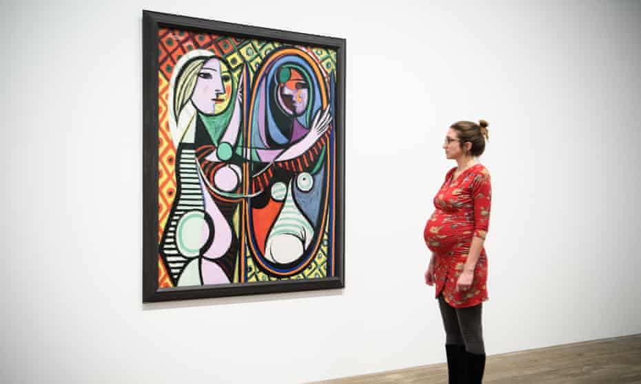 A woman looks at Girl before a Mirror (1932) by Pablo Picasso at the Tate Modern.