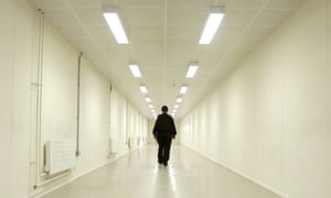A security officer patrols a corridor in an immigration removal centre.