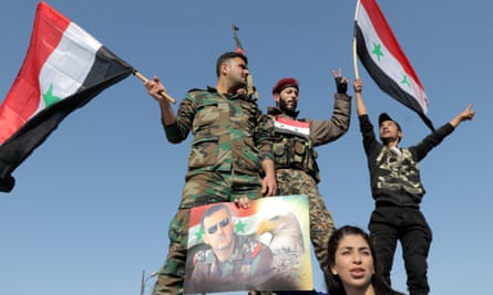 Syrian soldiers and civilians wave national flags during a gathering in Umayyad square in Damascus