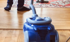 Rear view of man vacuuming carpet