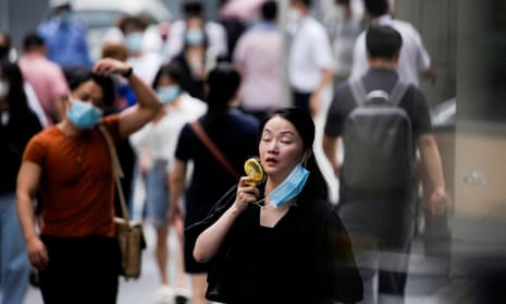 A woman wearing a face mask uses a fan as she walks on a street in Shanghai, China, as a severe heatwave continues to affect parts of the country.
