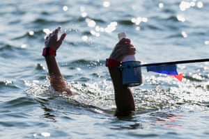 An open water swimmer reaching up from the water to grab a hydration bottle during a race in Singapore.