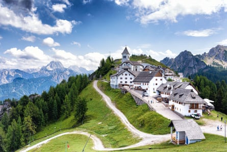 A white-washed village on a hill with mountains behind
