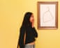 Woman with picture on wall of clothes hanger