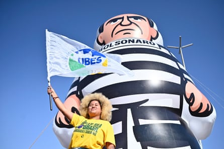 a woman waves a flag in front of a giant inflatable doll