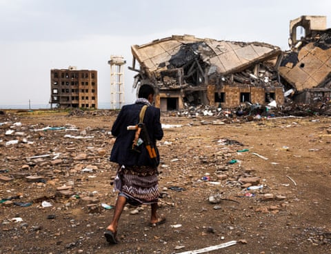 Mustafa al-Adel, a guard employed to watch over the ruins of the Dhamar detention facility, walks towards one of its bombed buildings.