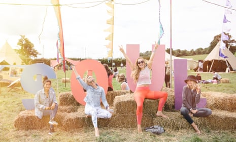 Guests at Soul Circus Festival, Cotswolds, pose in front of a sign spelling out the word soul, amid hazy sunshine.