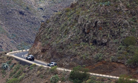Police vehicles parked on a road in rocky terrain