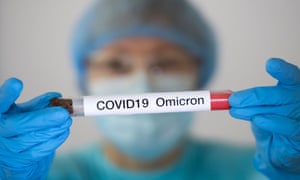 Woman in a protective suit and mask holding a test tube with a sample suspected to be infected with the Omicron Covid variant. Photograph by Maxym Marusenko/NurPhoto/Rex/Shutterstock